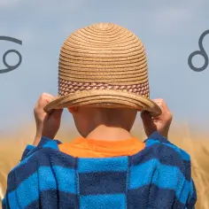 Chłopiec w słomkowym kapeluszu, z symbolami Raka i Lwa, sugeruje, że 8 lipca znak zodiaku to Rak, a nadchodzący Lew.
