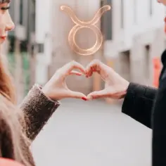 Dwie dłonie tworzą serce, a nad nimi unosi się symbol zodiaku Byk. Miłość między Bykiem a Rakiem kwitnie.