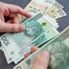 Dłonie liczą polskie banknoty 100 zł. Czy to zapowiedź finansowego sukcesu dla Ryb w horoskopie? Pieniądze w rękach.