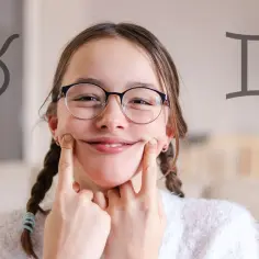 Uśmiechnięta dziewczyna z okularami, z dwoma symbolami zodiaku po bokach. Czyżby 21 maj znak zodiaku, czyli jej urodziny?