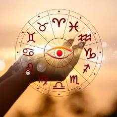 Dłonie trzymają koło zodiaku z okiem w centrum. 27 września znak zodiaku to Panna.
