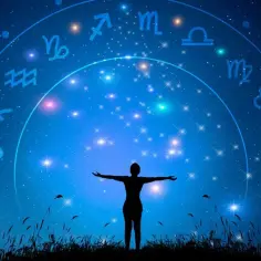 Sylwetka osoby z rozłożonymi rękami pod nocnym niebem pełnym gwiazd i znaków zodiaku. Listopad znak zodiaku jest widoczny na tle kosmicznego kręgu.