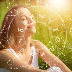 Uśmiechnięta kobieta w trawie, otoczona kołem zodiaku. Dziś horoskop dzienny lew czary przyniesie jej szczęście.