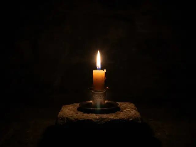 Płonąca świeca na kamieniu, symbolizująca północ, 00:00 znaczenie.